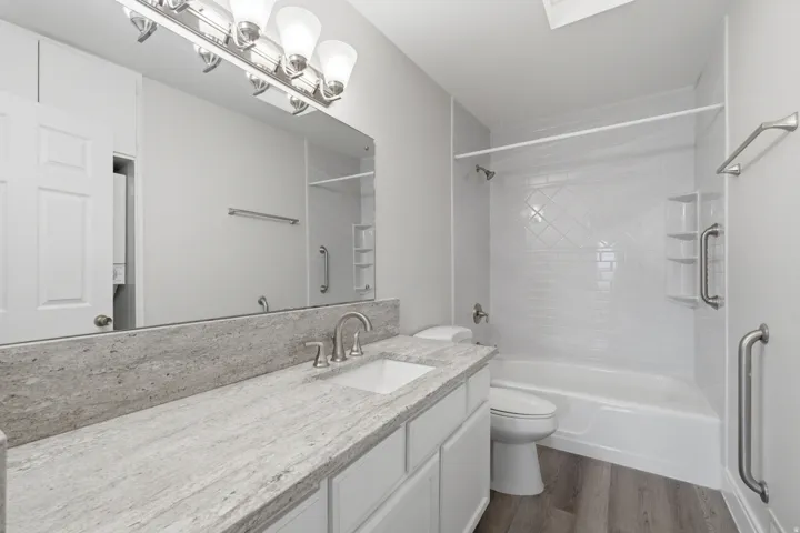 Bathroom featuring a white vanity with a stone countertop, an integrated rectangular sink, and a large mirror