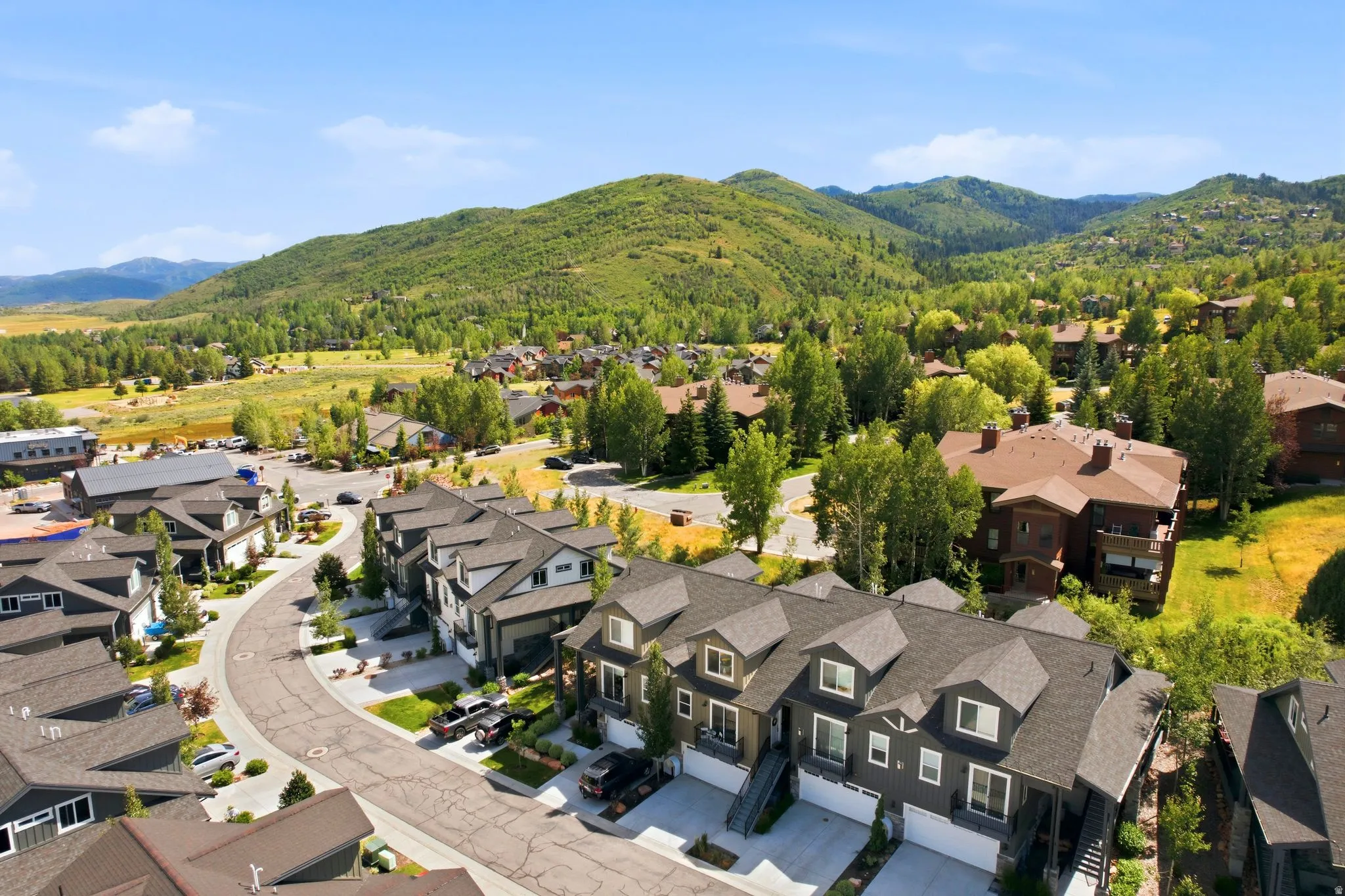 Residential community featuring a curved street, multiple townhomes with dormer windows, and attached garages