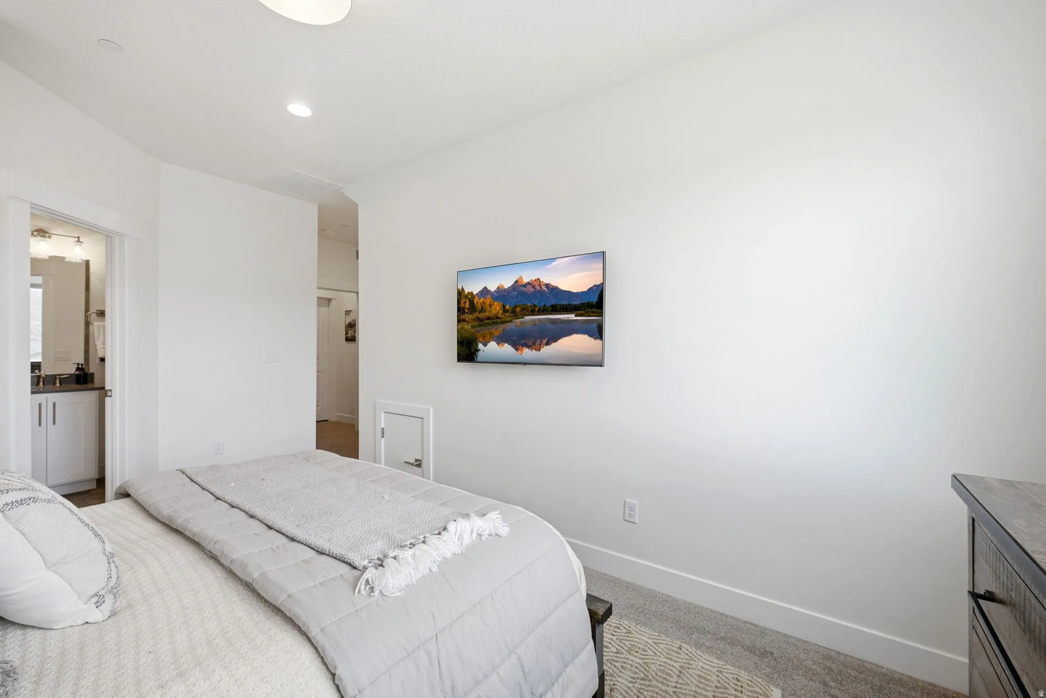 Carpeted bedroom with crisp white walls and ceiling, featuring recessed lighting and a ceiling light fixture