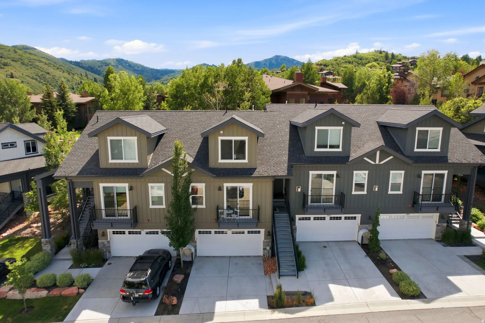 Contemporary multi-level townhome featuring a dark shingle roof and dormer windows