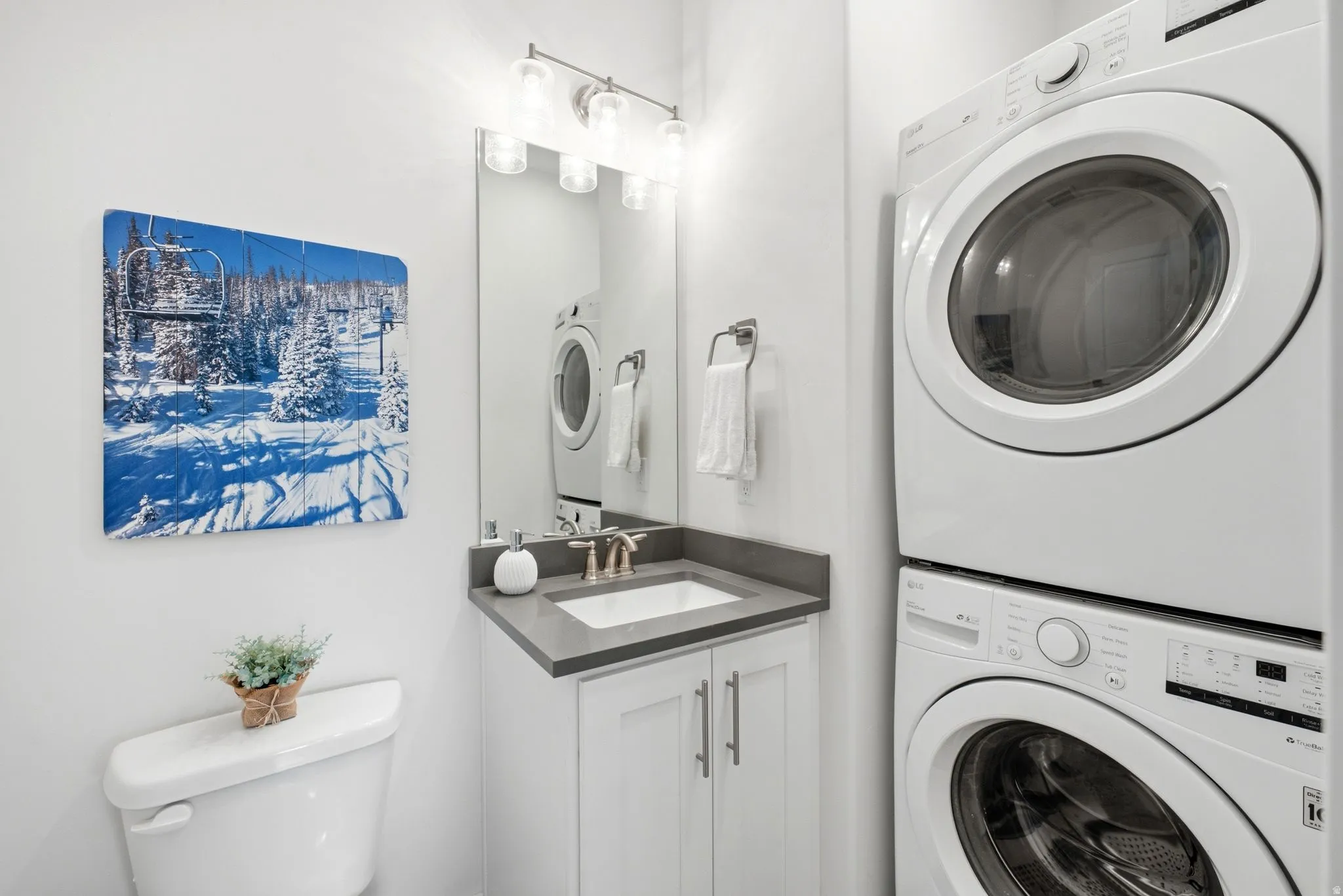 Powder room featuring a stacked washer and dryer, a vanity with a dark countertop and undermount sink, and a wall-mounted light fixture
