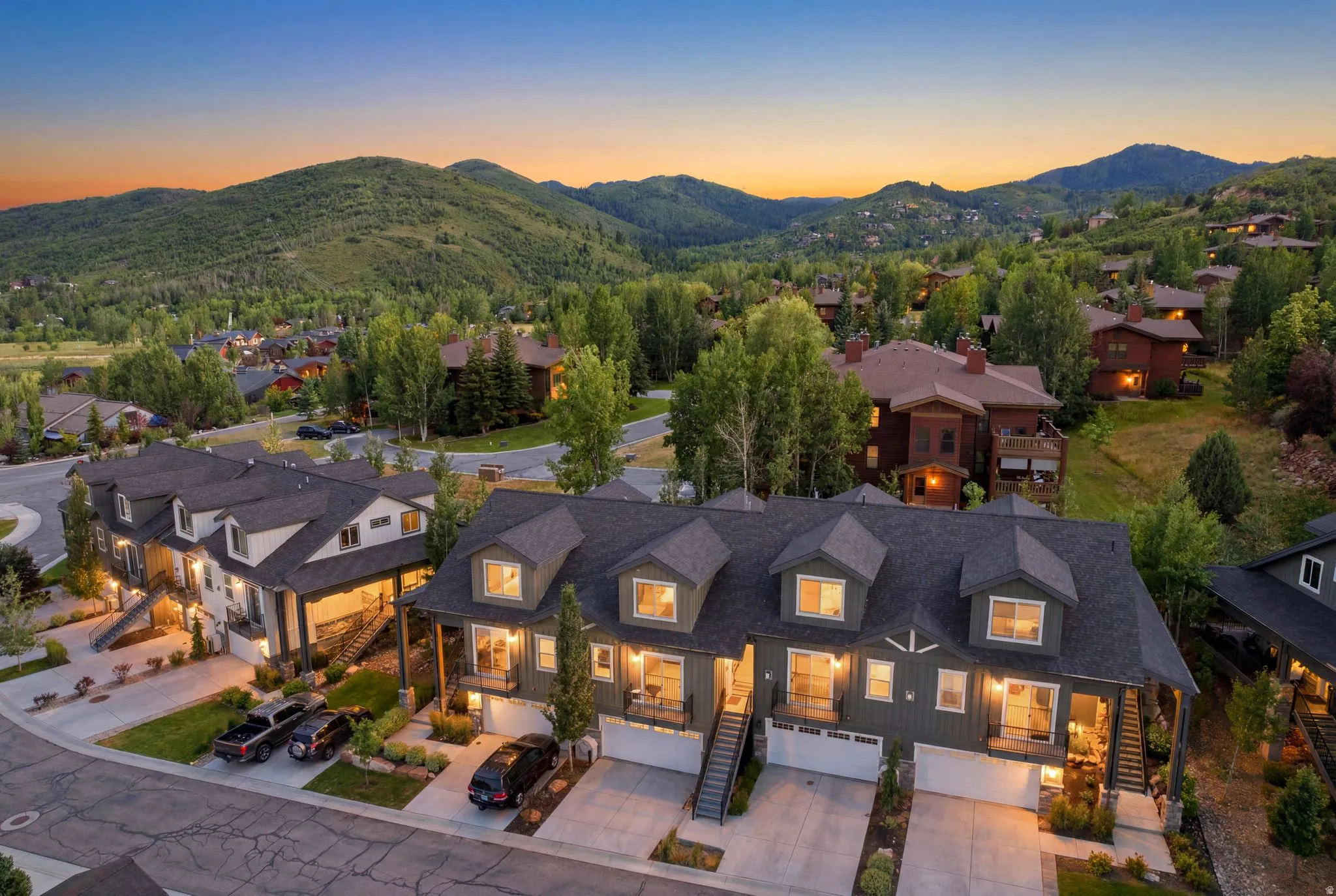Townhome row featuring dark gray siding, white garage doors, and individual covered entryways