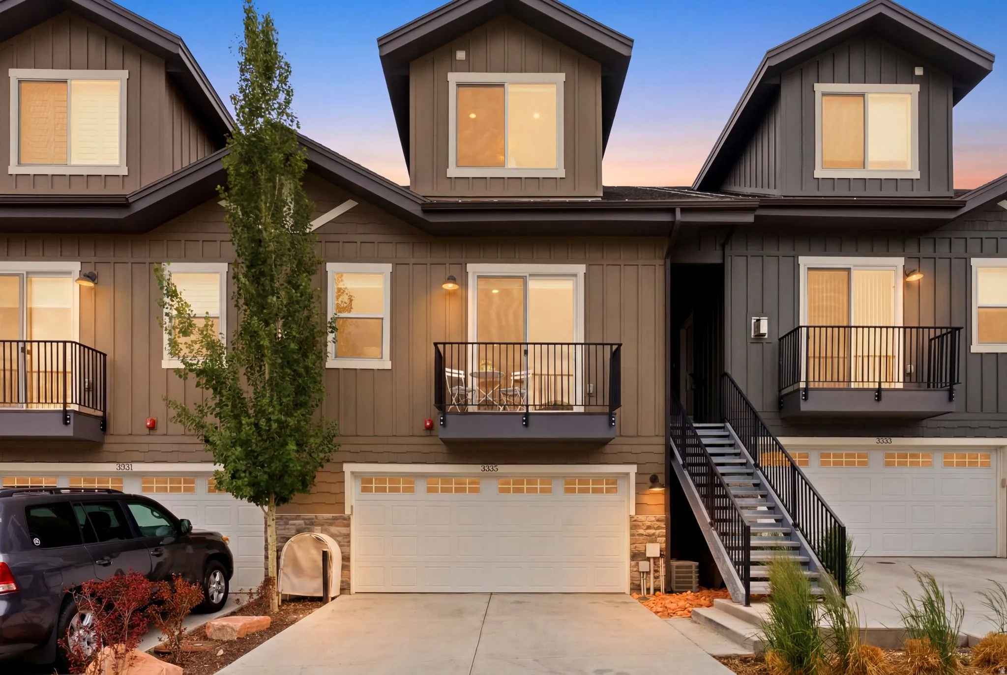 Modern townhome exterior featuring vertical siding, dormer windows, and a private balcony
