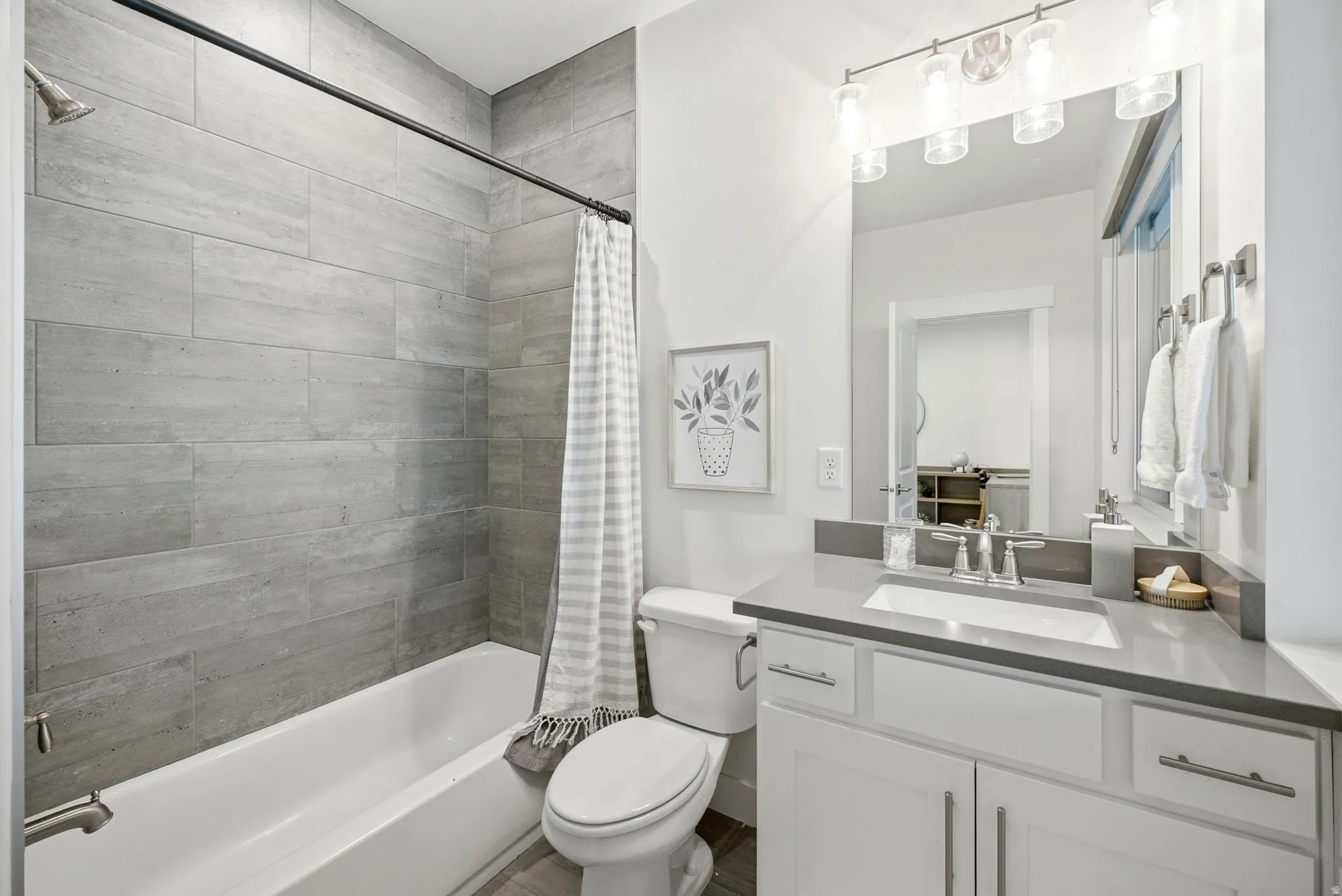 Bathroom featuring a white vanity with a gray countertop, an undermount sink, and a modern light fixture