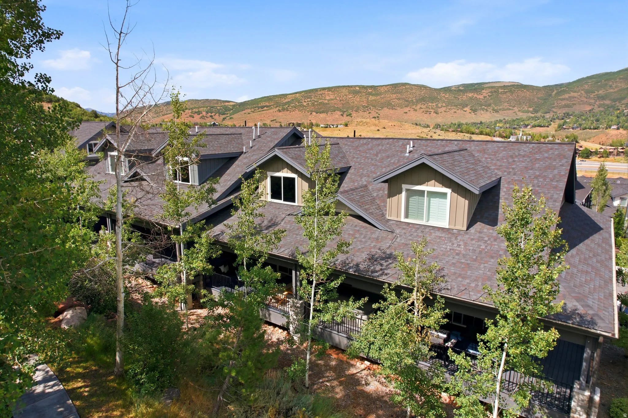 Townhome exterior featuring dormer windows, a dark shingle roof, and a covered balcony