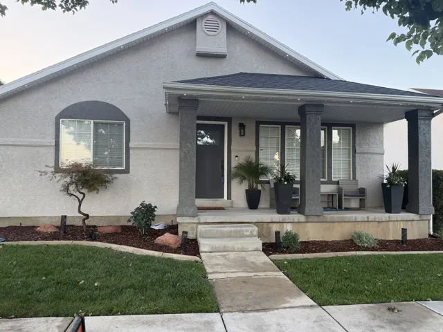 Stucco exterior featuring an arched window, dark gray columns, and a covered porch