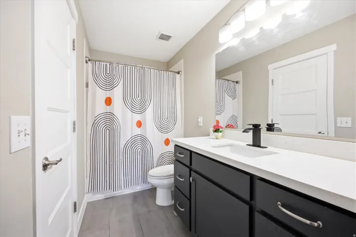 Bathroom featuring a black vanity with a white countertop, rectangular undermount sink, and matte black faucet