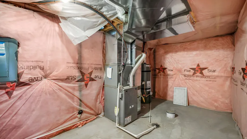 Basement utility area with concrete flooring, exposed ceiling joists, and insulated walls