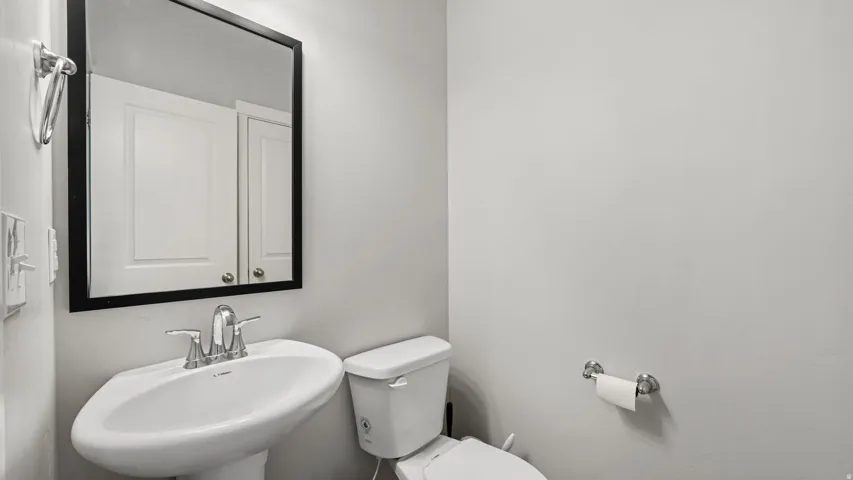Pedestal sink with chrome faucet, framed mirror, and white wall-mounted storage cabinet