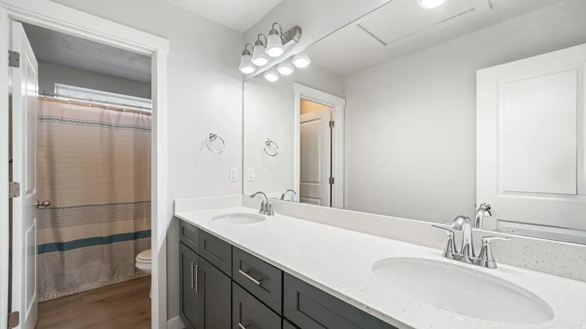 Bathroom featuring a dual vanity with white countertops, undermount sinks, and chrome faucets