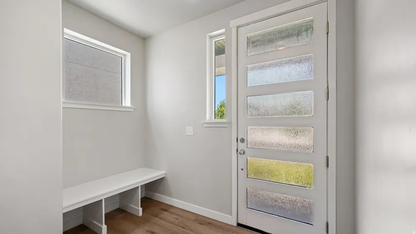 Entryway featuring a modern door with multiple textured glass panels, two additional windows, and a built-in bench with storage cubbies