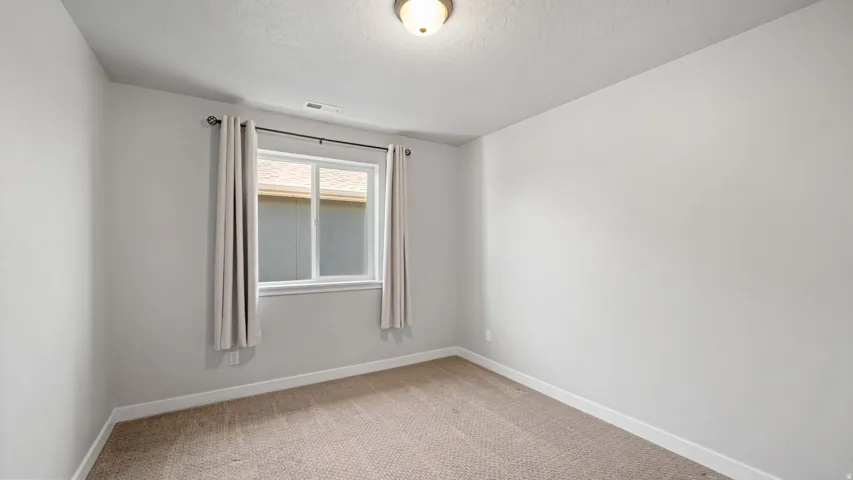 Neutral-toned interior room featuring light gray walls, white trim, and a window with white casing
