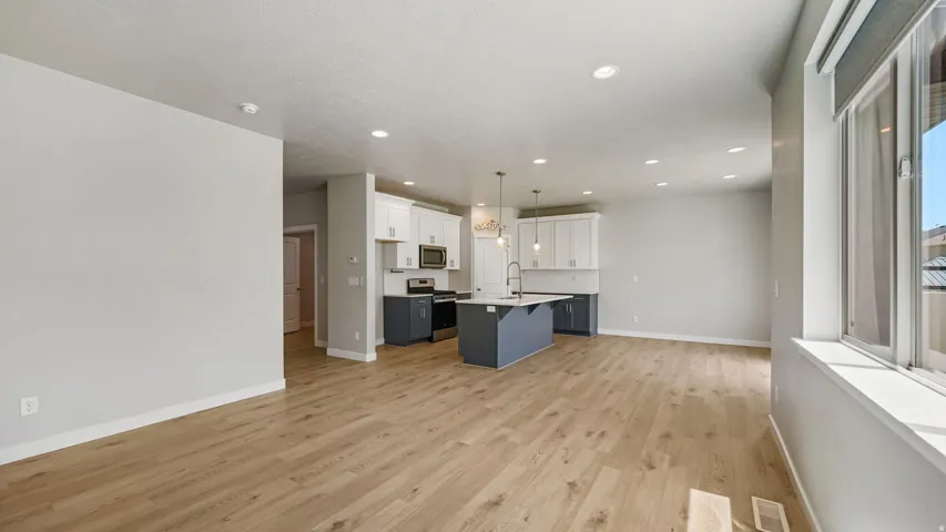 Open-concept kitchen and living area featuring wood-finish flooring, recessed lighting, and a kitchen island with pendant lighting