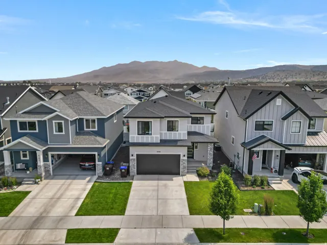 Contemporary two-story residence featuring a two-car garage, dark asphalt shingle roof, and a stone façade accent