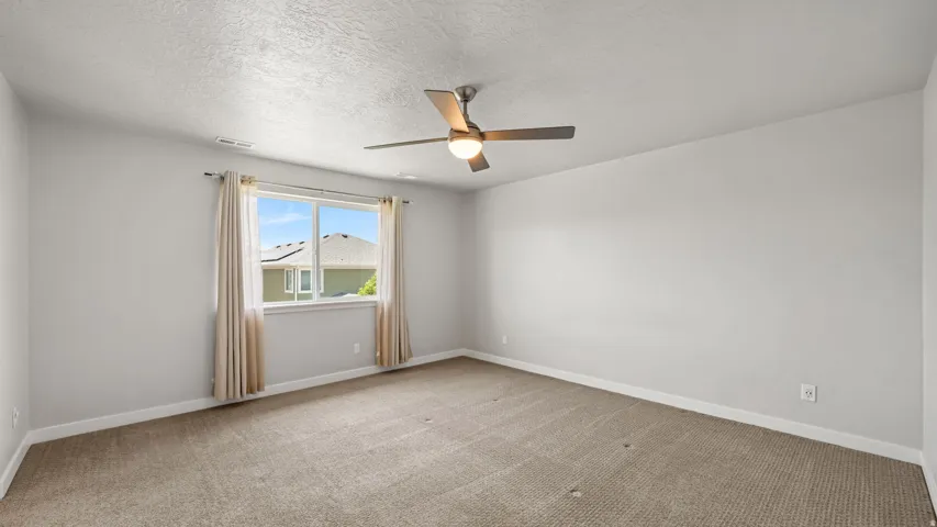 Spacious room with light-colored carpeting and neutral wall paint