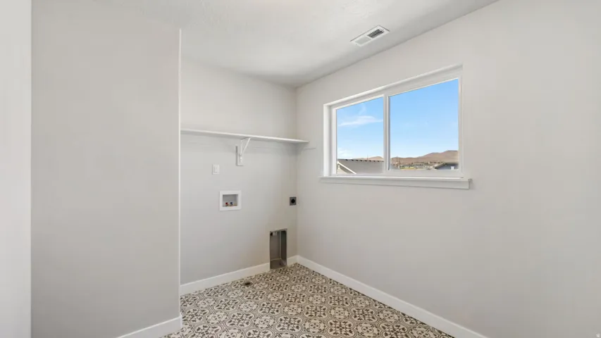 Utility room featuring patterned floor tiling, a single window, and a white wall shelf