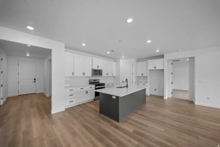 Spacious kitchen featuring white shaker cabinetry, stainless steel appliances, and a central island with a contrasting base and light-toned countertop