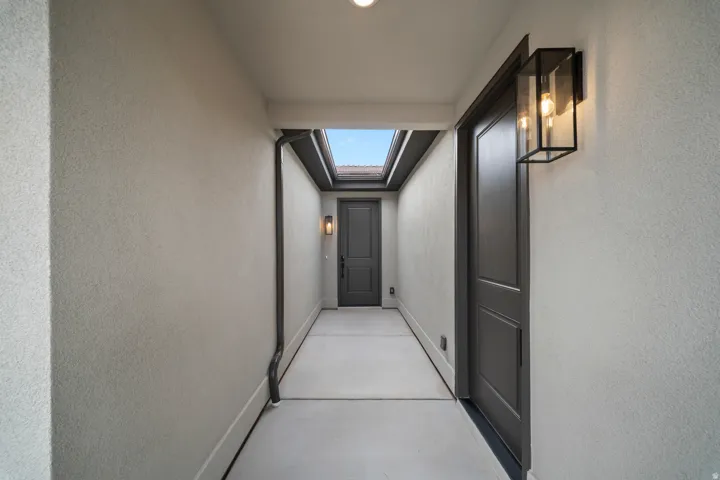 Covered walkway with stucco walls, recessed lighting, and a skylight feature