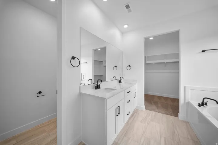 Bathroom featuring a double vanity with stone countertop, undermount sinks, and matte black fixtures