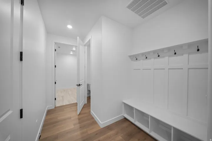 Entryway mudroom featuring built-in white cabinetry with a bench, storage cubbies, and coat hooks