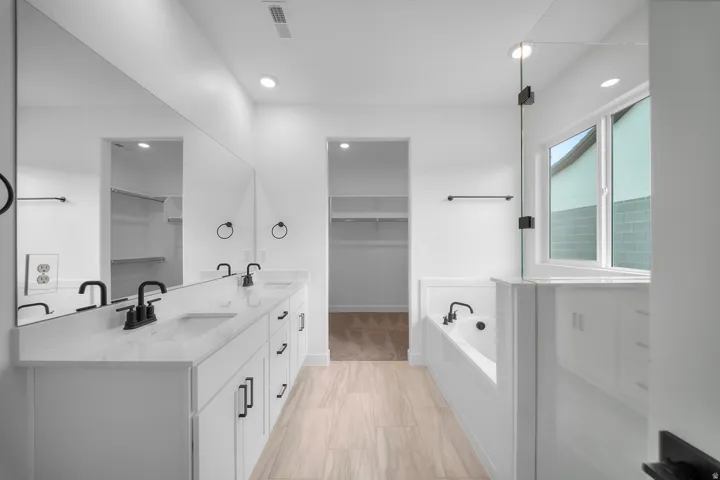 Bathroom featuring a dual vanity with white cabinetry, rectangular undermount sinks, and black fixtures