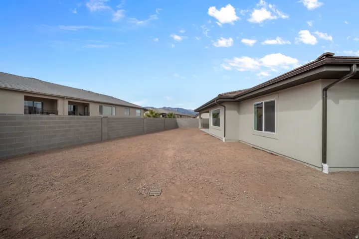 Expansive rear yard featuring an unfinished surface ready for customization, a stucco exterior, multiple windows, and a block wall perimeter