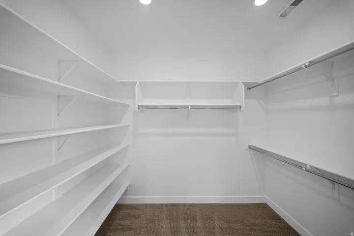 Walk-in closet featuring extensive white shelving and multiple hanging rods for organization