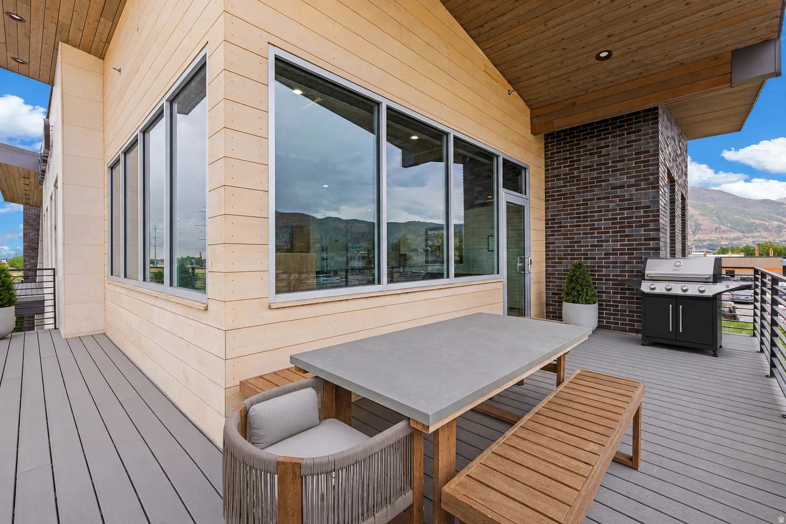 Expansive outdoor deck featuring composite decking, wood-finish siding, and a partial wood-paneled ceiling