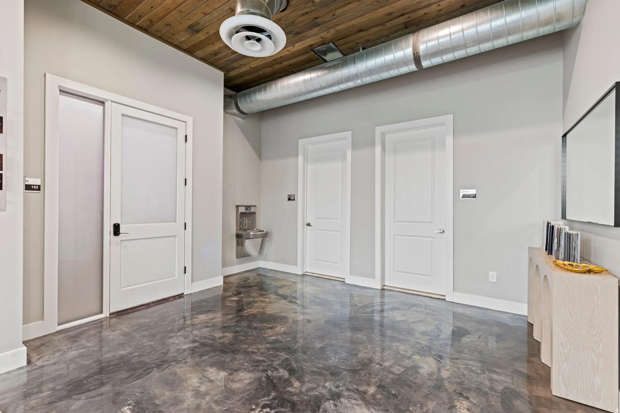 Polished concrete flooring complemented by a rich wood-plank ceiling