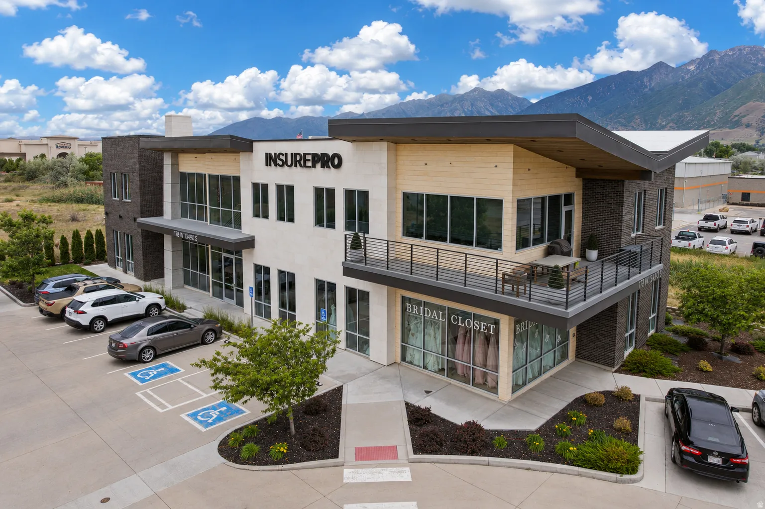 Modern commercial building featuring a multi-textured facade with stone, light-colored paneling, and wood-finish accents