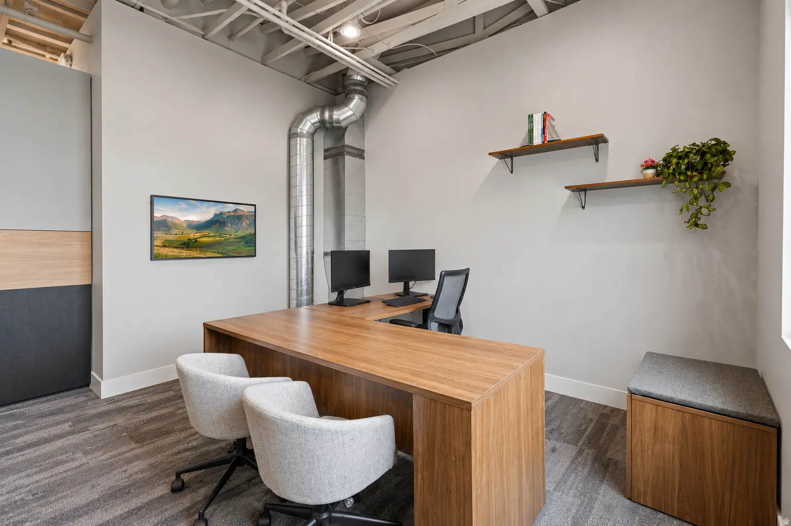 Contemporary office space featuring wood-finish flooring, exposed ceiling ductwork, and built-in shelving