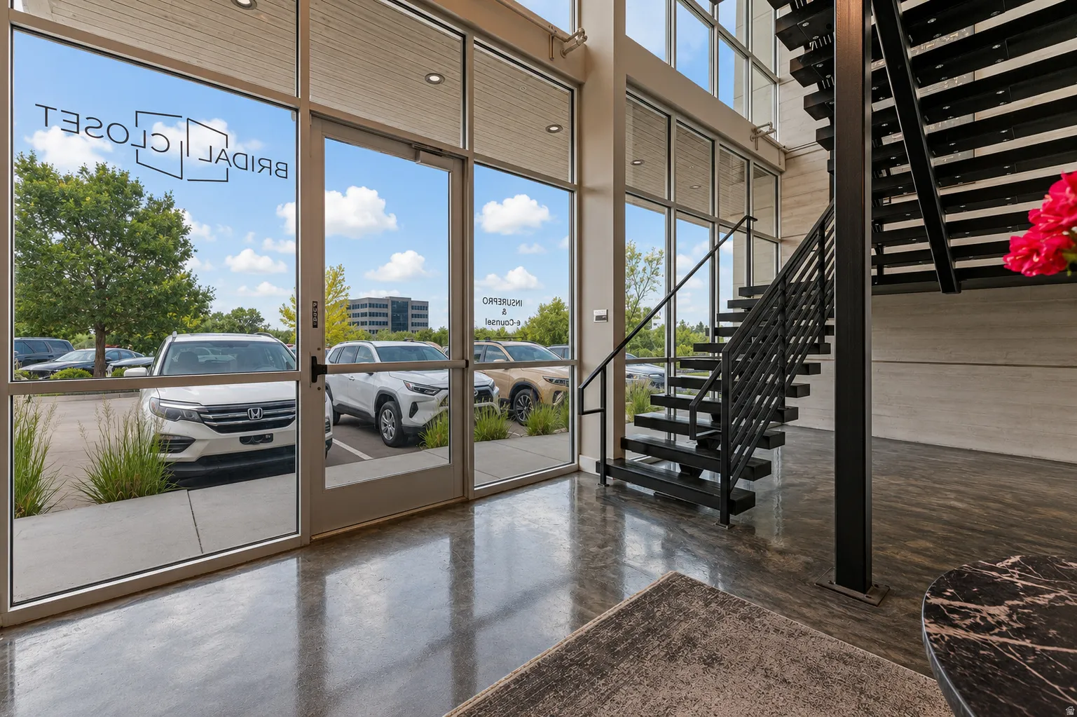 Modern entrance featuring a black metal staircase with open risers, polished concrete flooring, and extensive window walls