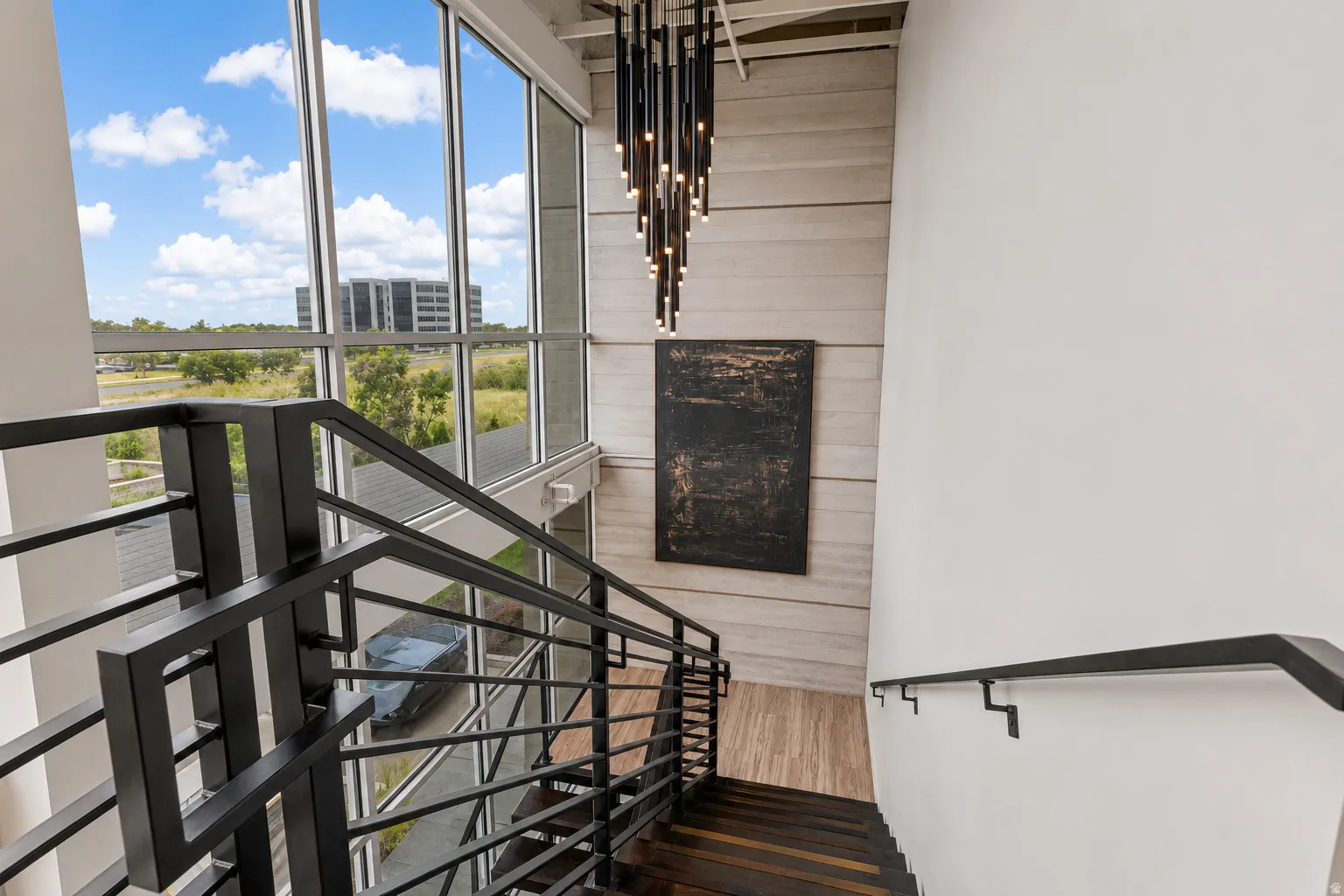 Contemporary staircase featuring dark wood-finish treads and risers, complemented by a sleek black metal railing and a wall-mounted handrail