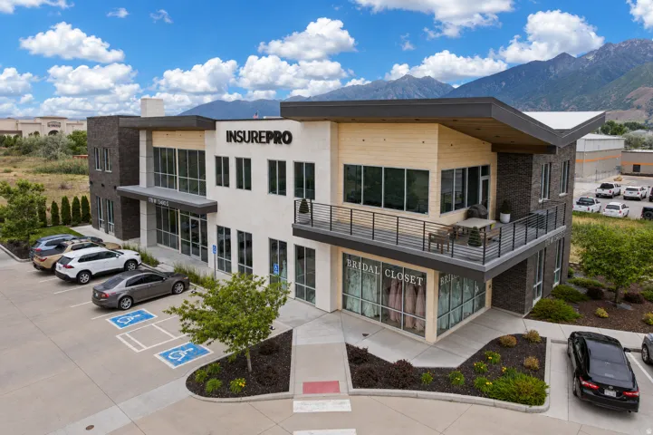 Modern commercial building featuring a multi-textured facade with stone, light-colored paneling, and wood-finish accents