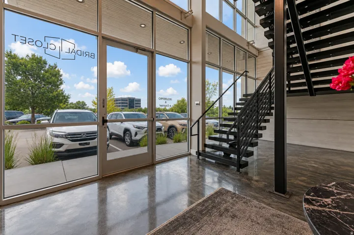 Modern entrance featuring a black metal staircase with open risers, polished concrete flooring, and extensive window walls