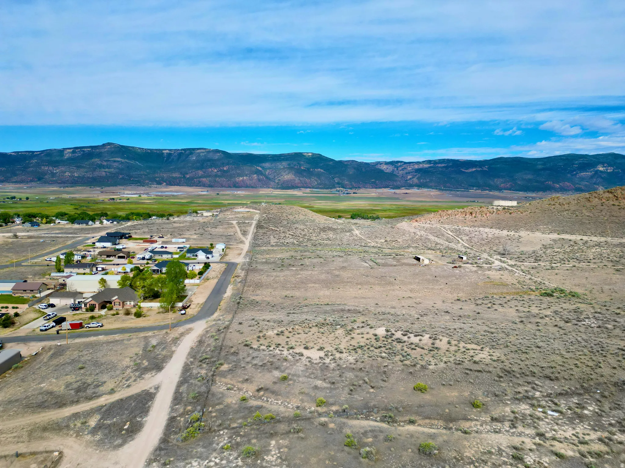 Expansive undeveloped land featuring natural desert vegetation, unpaved roads, and distant mountain ranges