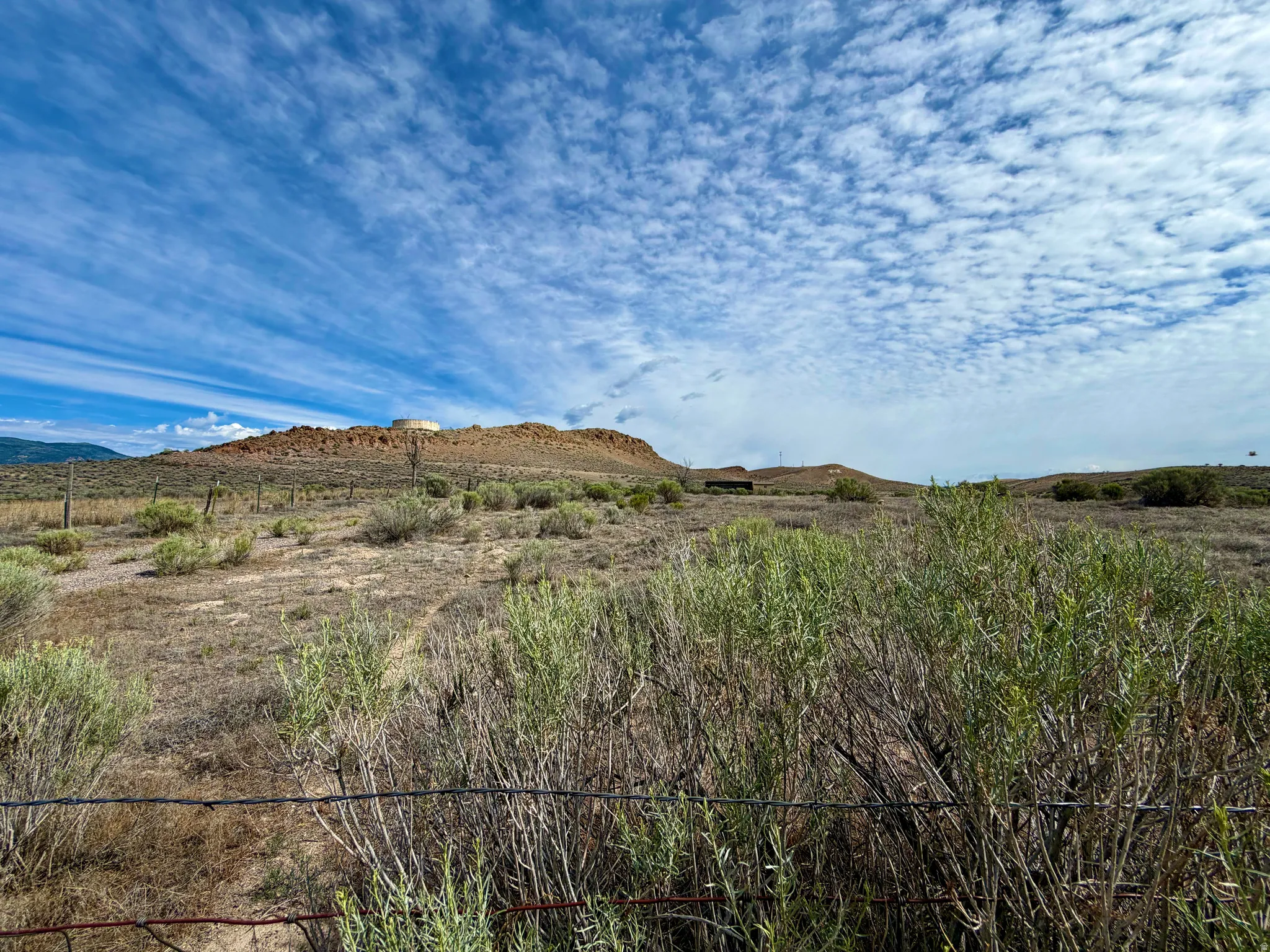 Expansive land parcel featuring natural desert flora, distant rolling hills, and a prominent mesa formation