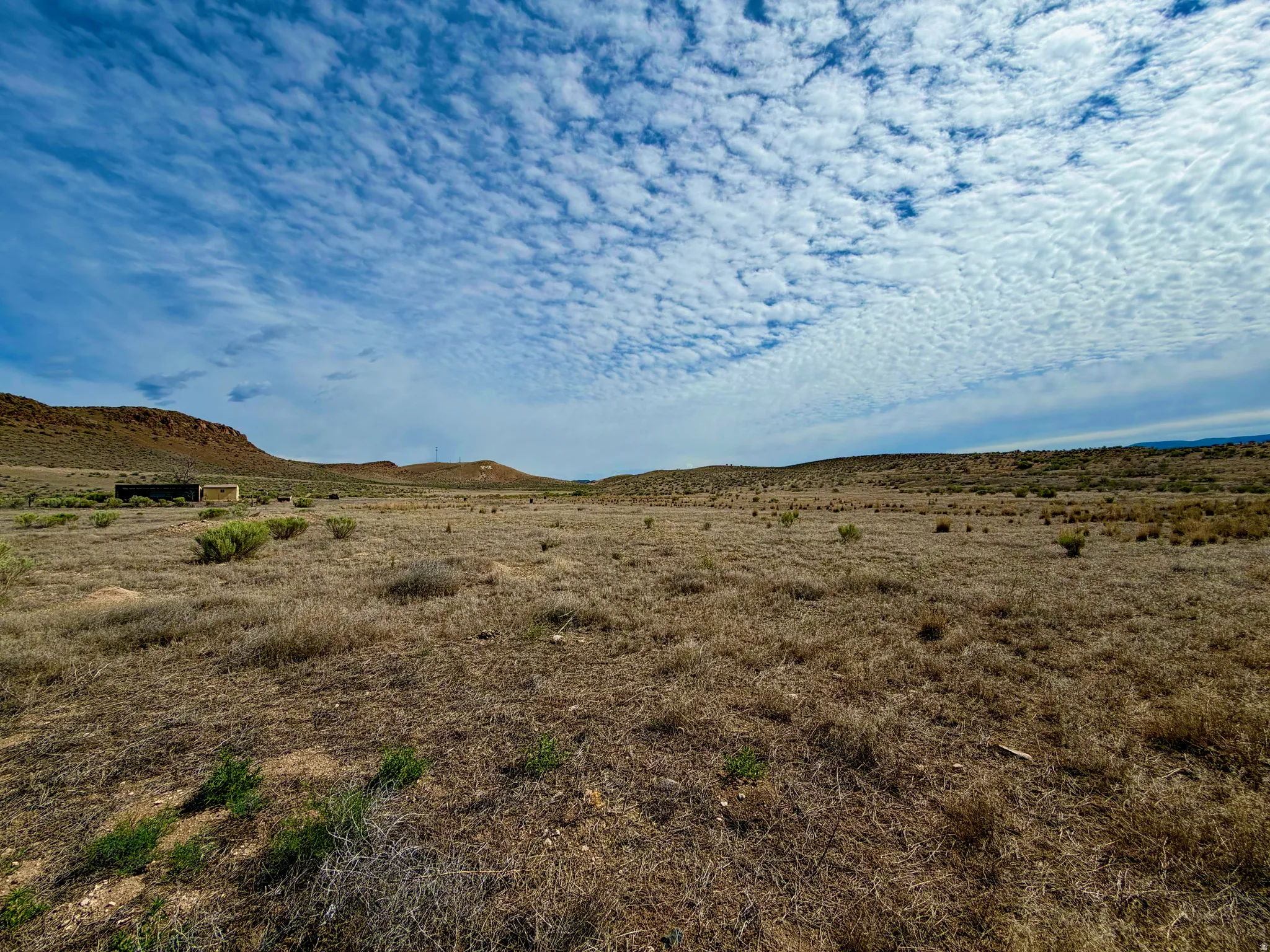 Expansive undeveloped land featuring natural desert vegetation and distant hills