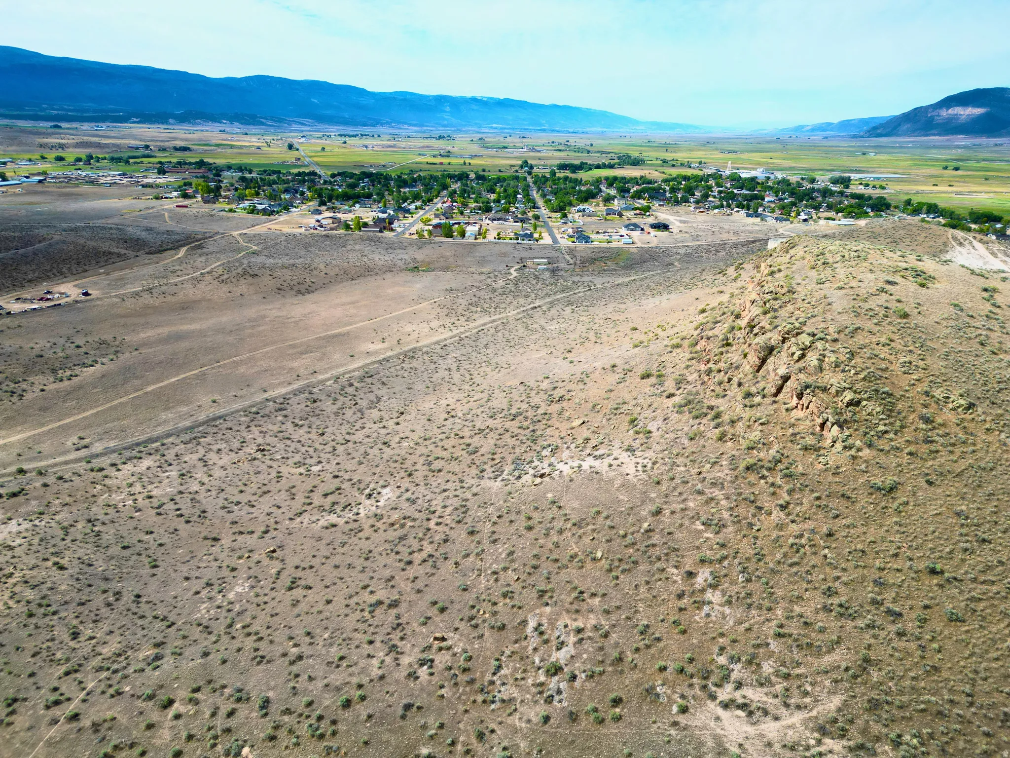 Expansive arid terrain featuring a prominent rocky outcrop and distant mountain ranges