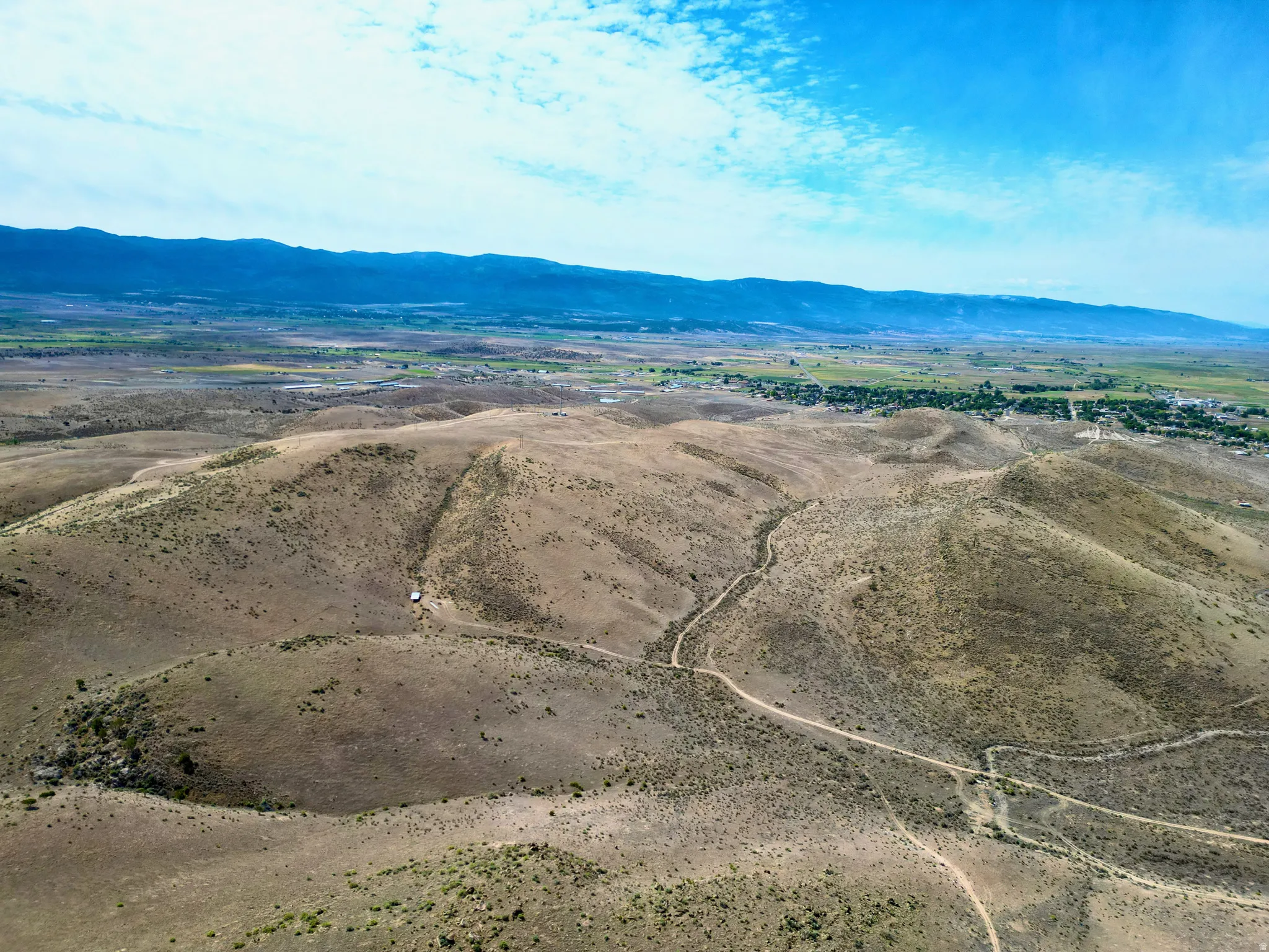 Expansive arid landscape featuring rolling hills and distant mountainous terrain