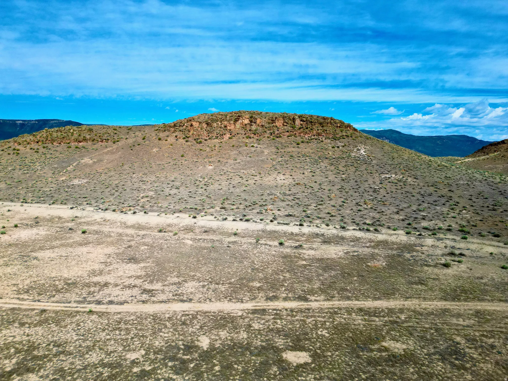 Expansive desert landscape featuring a prominent mesa with visible rock formations