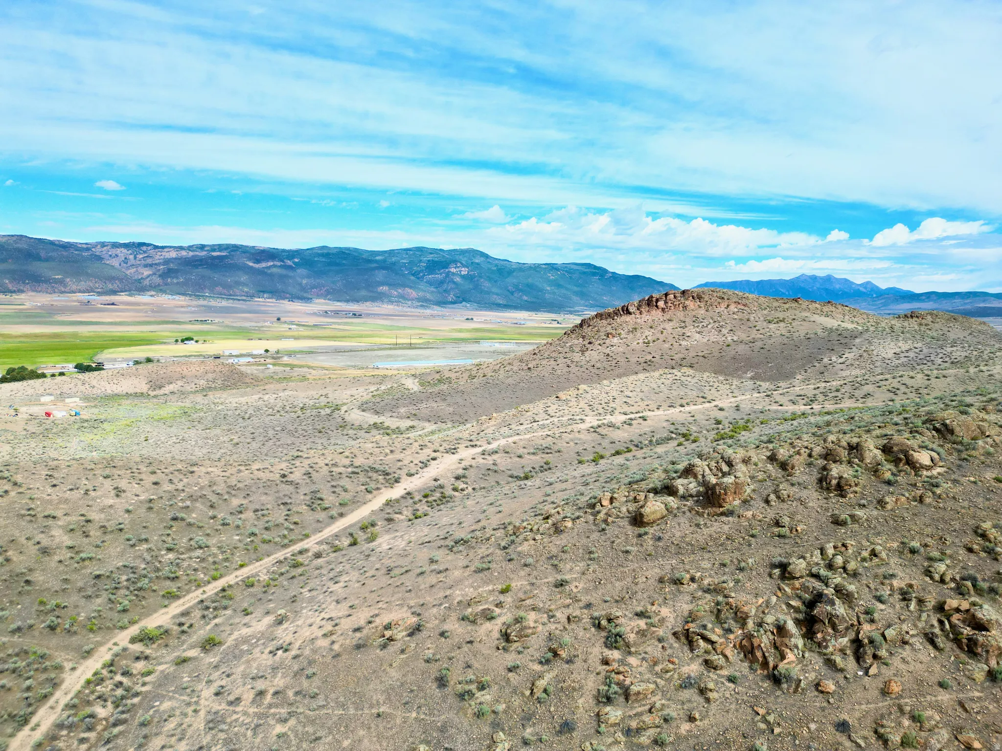Expansive land parcel featuring a rugged, elevated terrain and a visible dirt path