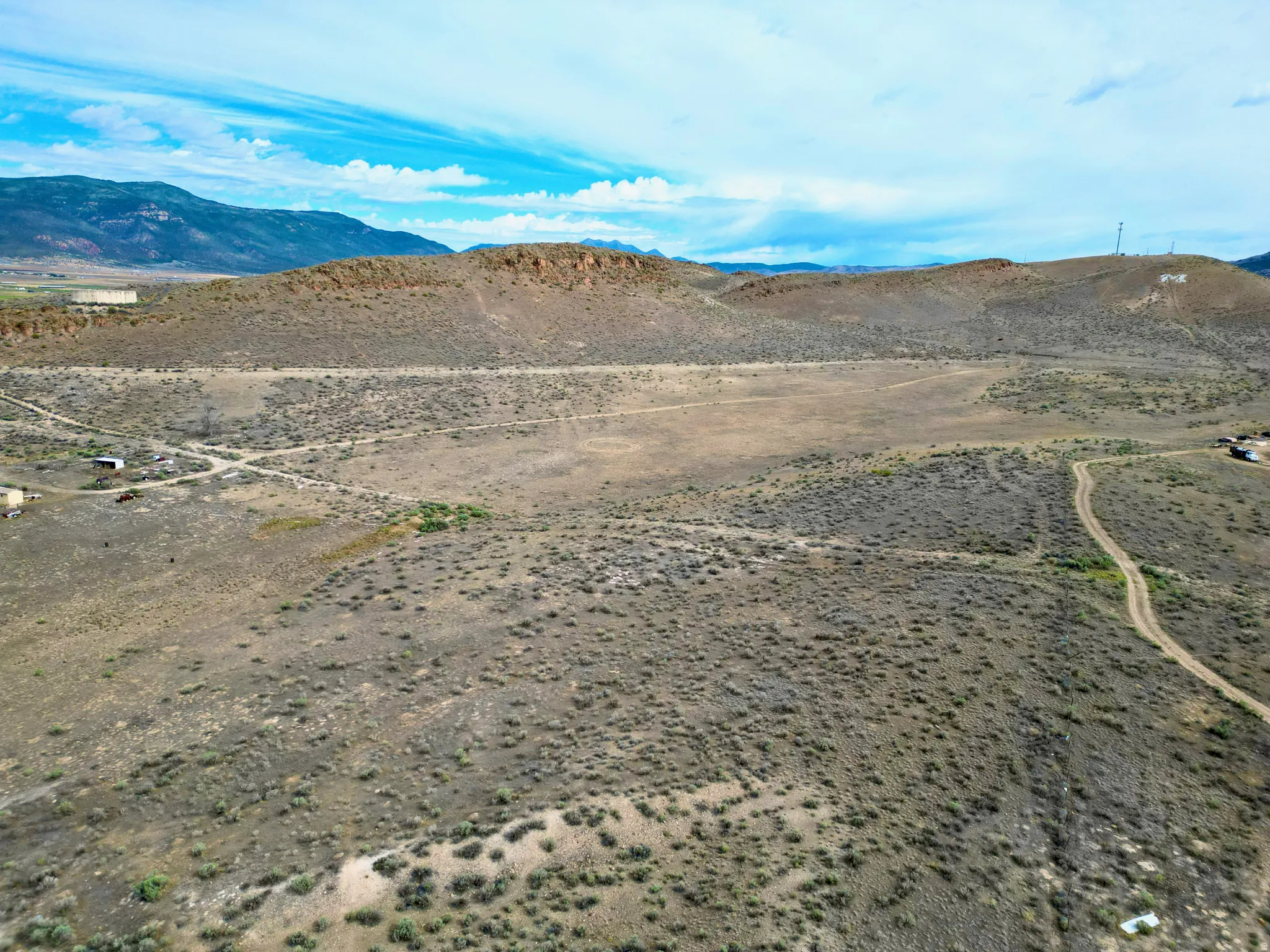 Expansive undeveloped land featuring natural desert vegetation, rolling hills, and distant mountain ranges