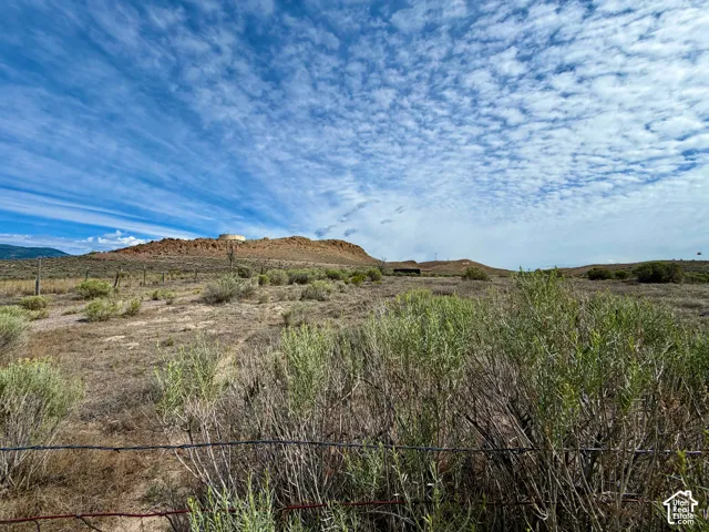 Expansive land parcel featuring natural desert flora, distant rolling hills, and a prominent mesa formation