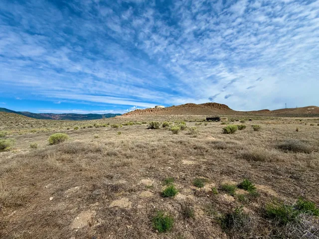 Expansive land parcel featuring natural, arid vegetation and distant mountainous terrain