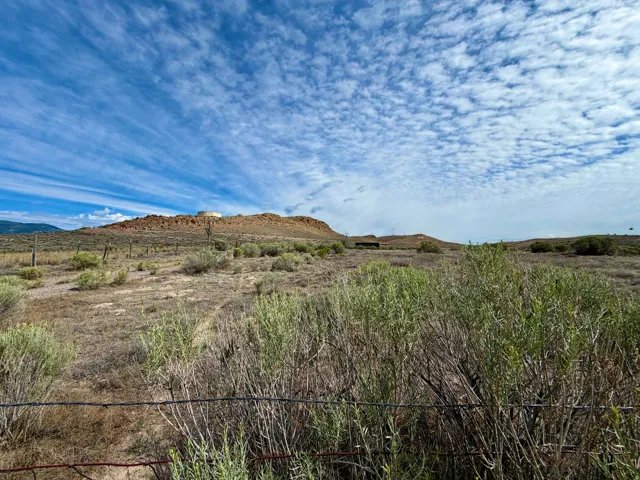 Expansive land parcel featuring natural desert flora, distant rolling hills, and a prominent mesa formation