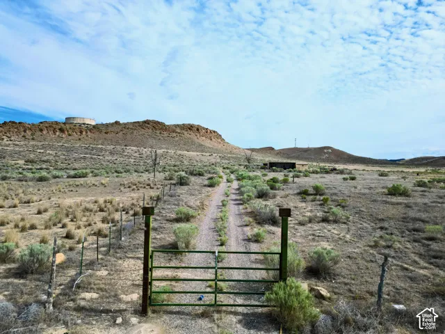 Gated property entrance with a dirt road extending into the distance, framed by natural desert flora