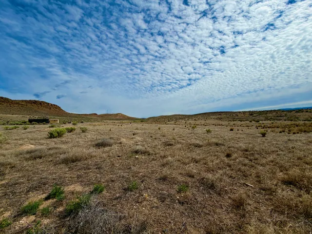 Expansive undeveloped land featuring natural desert vegetation and distant hills