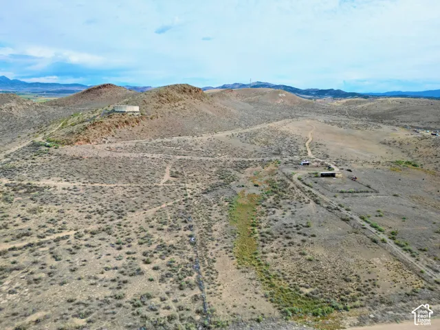 Expansive desert landscape featuring rolling hills, scattered brush, and unpaved pathways