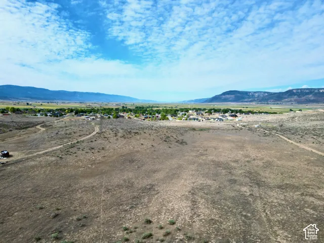 Expansive undeveloped terrain with distant residential structures and mountain ranges